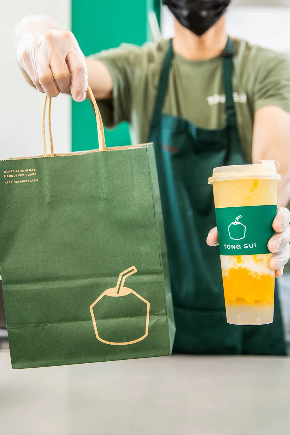Tong Sui employee holding a paper bag and a drink.